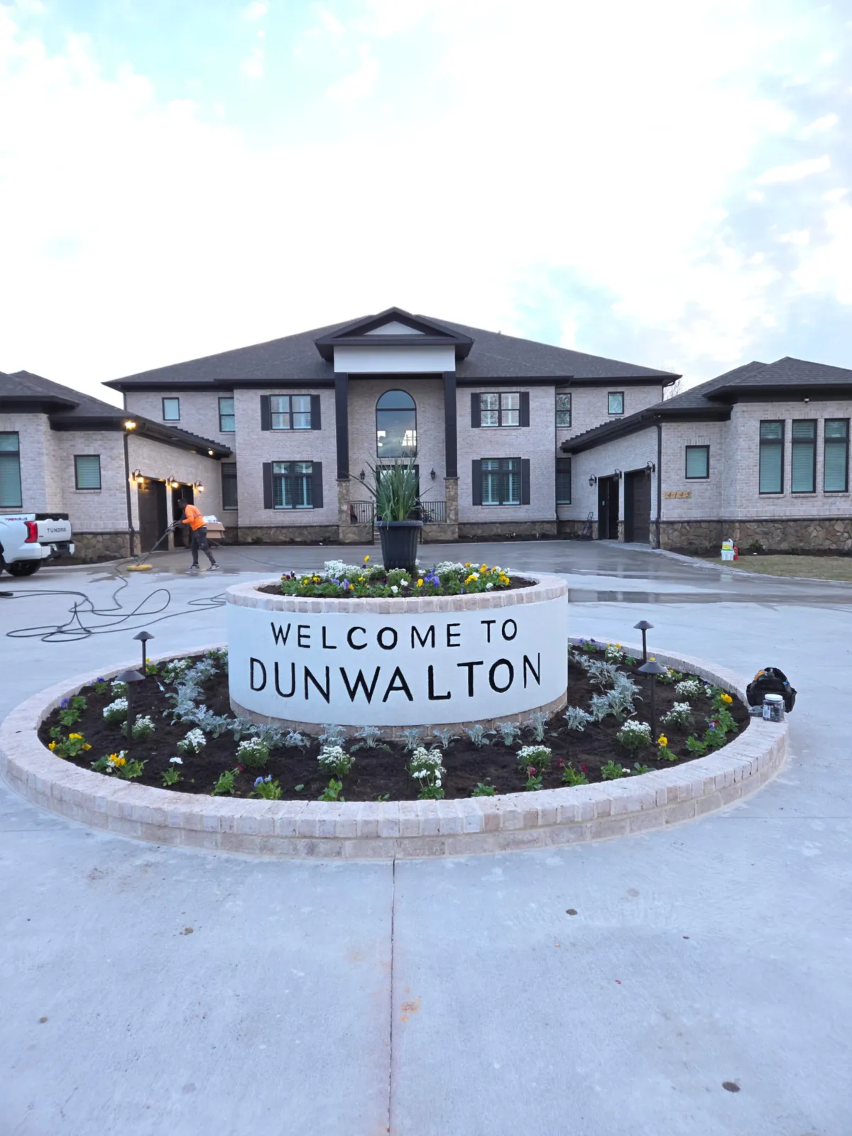 Welcome to Dunwalton entrance sign with a planted circular bed and fresh mulch