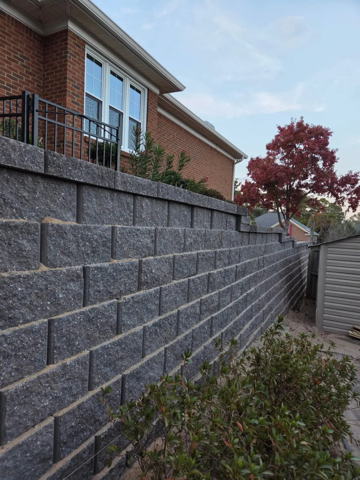 Segmental block retaining wall holding a grade beside a brick home